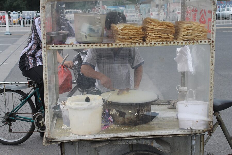 Beijing street vendor preparing jianbing breakfast crepe