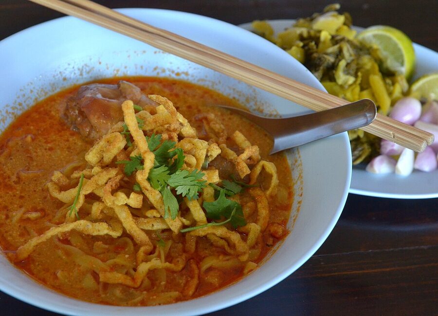 Chicken khao soi in a rustic bowl, topped with fried crispy noodles
