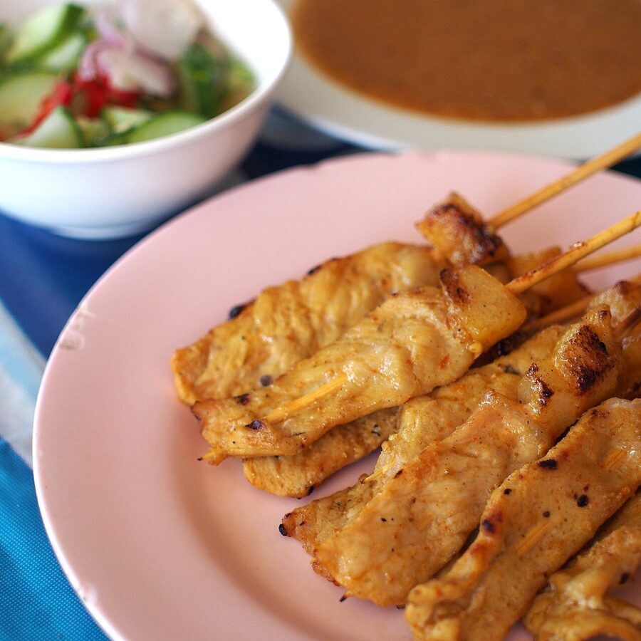 Pork satay skewers grilling over charcoal at a Thai food market
