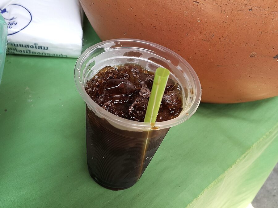 Oliang traditional Thai iced coffee served in a tall plastic cup with condensed milk layer
