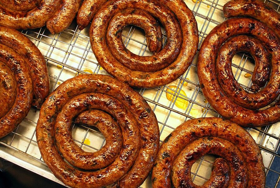 Market vendor grilling sai ua northern Thai pork sausage over charcoal in Chiang Mai
