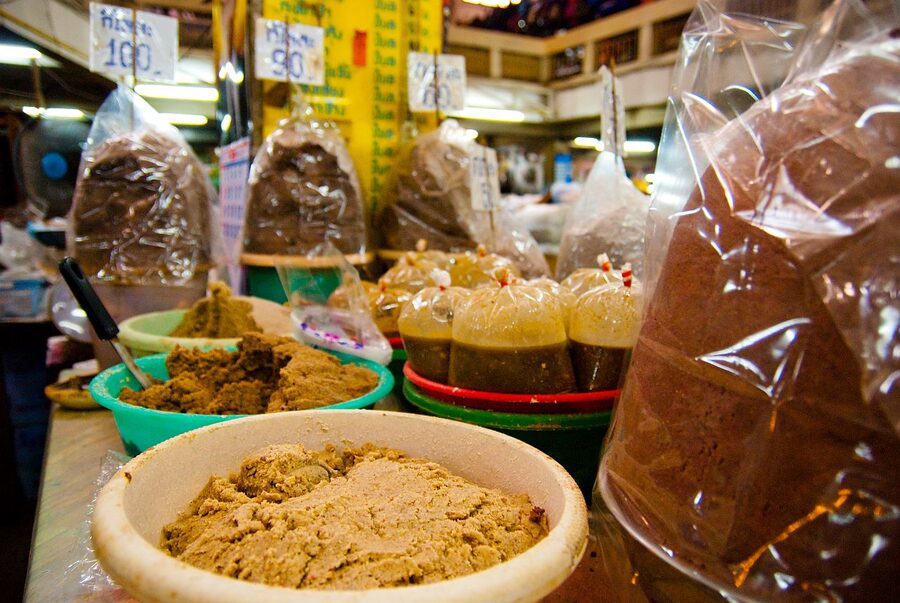 Shrimp paste kapi vendor at Warorot Market in Chiang Mai, with baskets of dried chili and spices