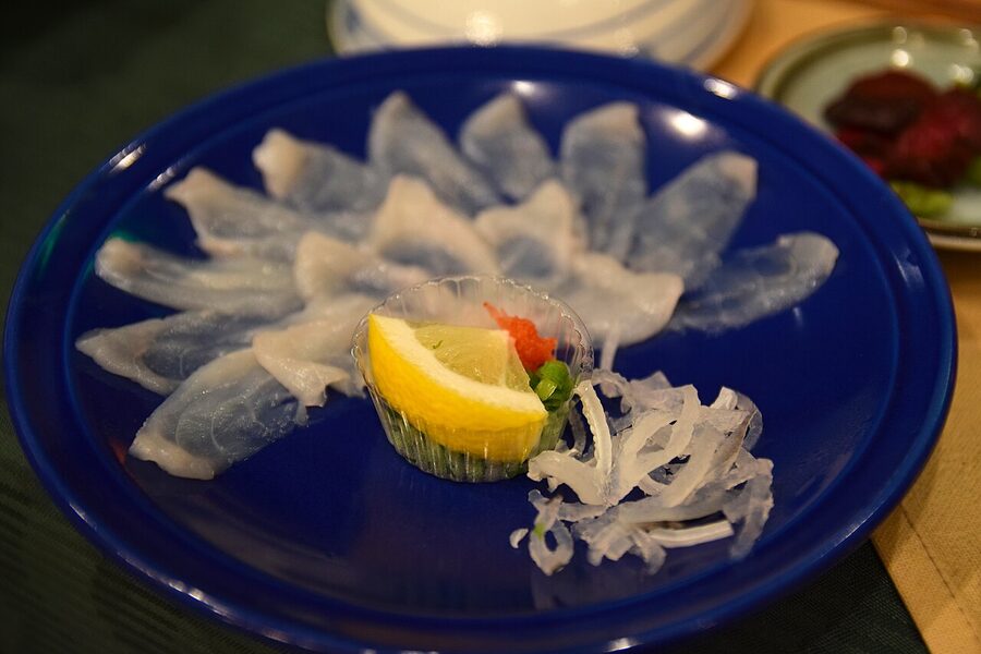 Thinly sliced fugu sashimi arranged in a chrysanthemum pattern on a plate