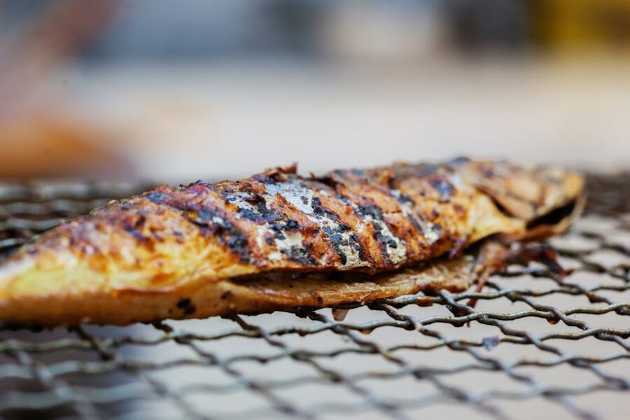 A whole fish grilling over charcoal