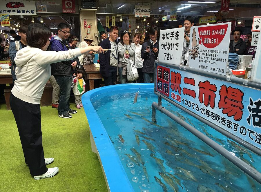 A vendor preparing freshly-caught squid at the Hakodate Morning Market in Hokkaido