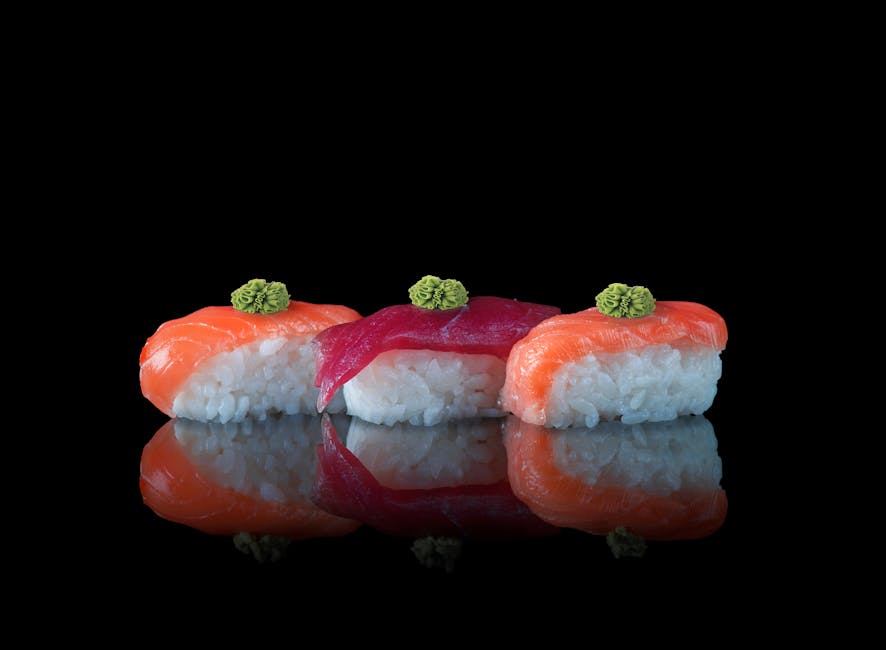 A close-up of nigiri sushi with salmon and tuna topped with wasabi