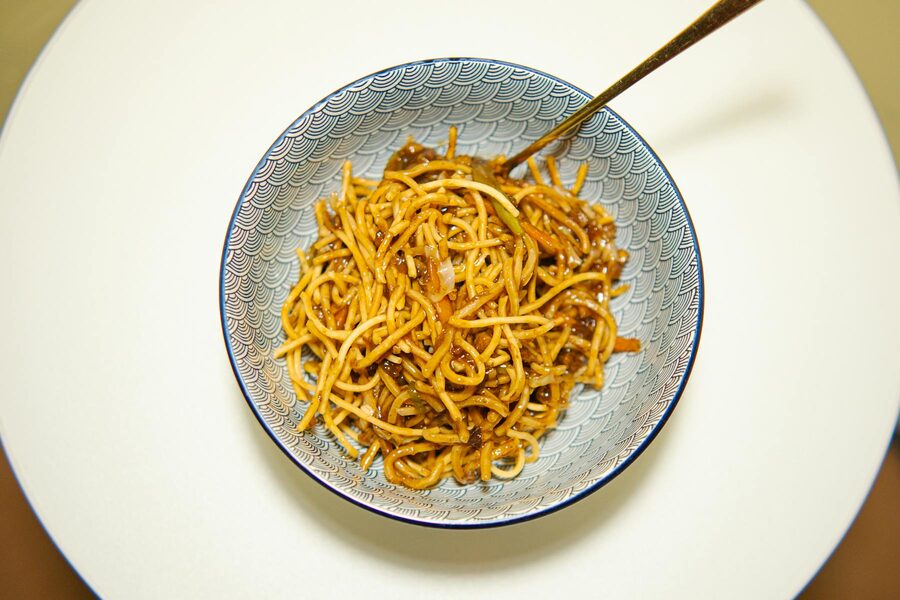 Chinese noodles in a decorative bowl with chopsticks