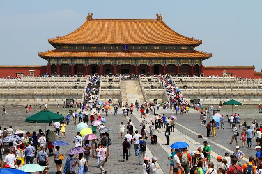 Tourist crowds in a Forbidden City courtyard with imperial buildings in the background, Beijing