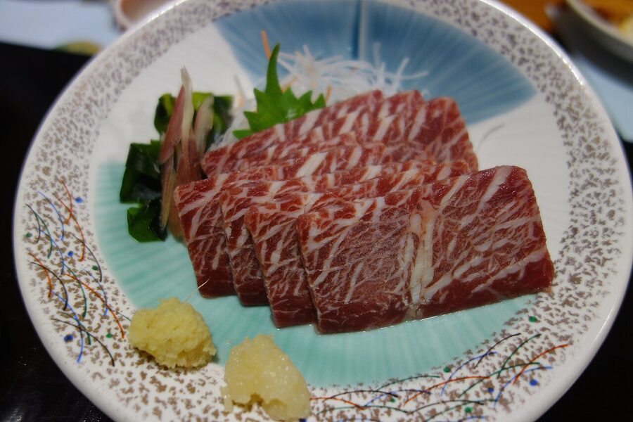 Basashi horse sashimi with ginger and garlic on a wooden plate