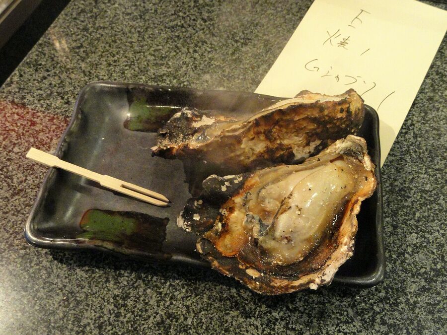 Large grilled Japanese oysters served on a plate in Miyajima