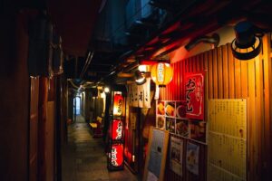 Narrow Japanese izakaya alley decorated with hieroglyphs and lanterns in the evening