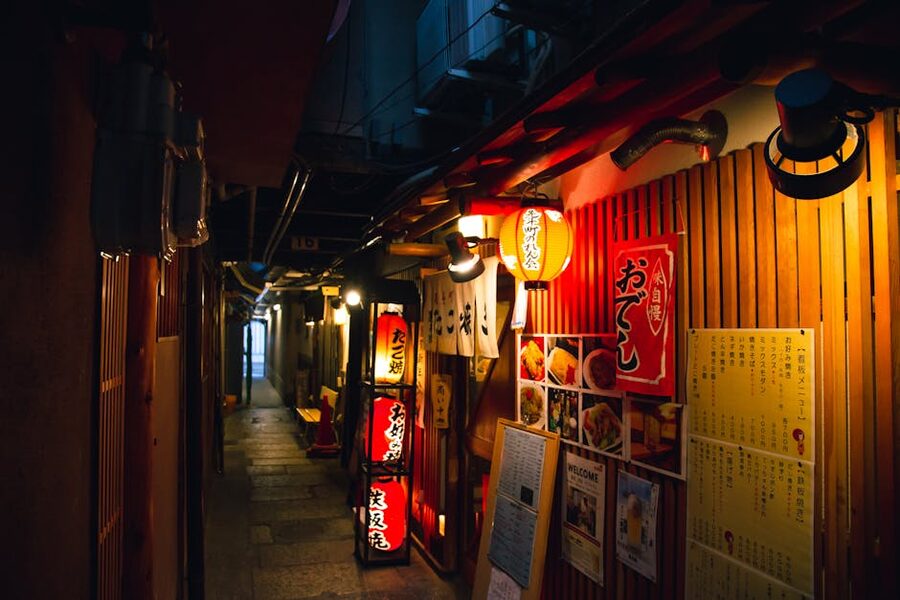 Narrow Japanese izakaya alley decorated with hieroglyphs and lanterns in the evening