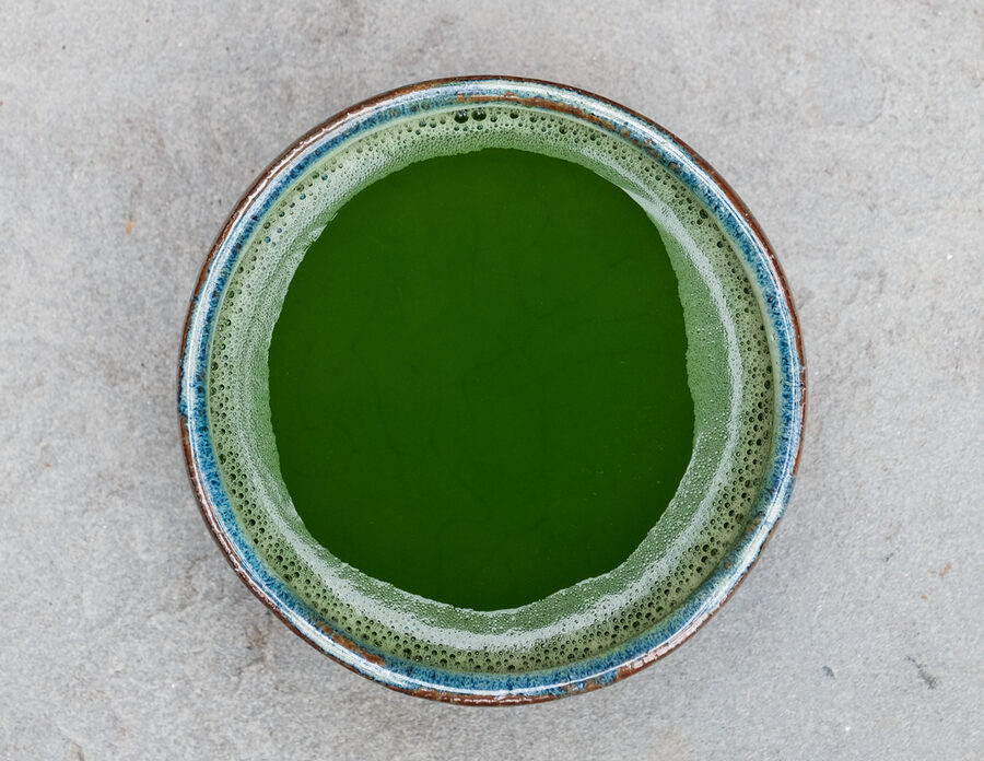 Bowl of ceremonial matcha tea with bamboo whisk