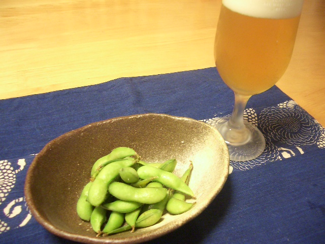 Glass of cold Japanese beer next to a bowl of edamame, the classic izakaya opening combination