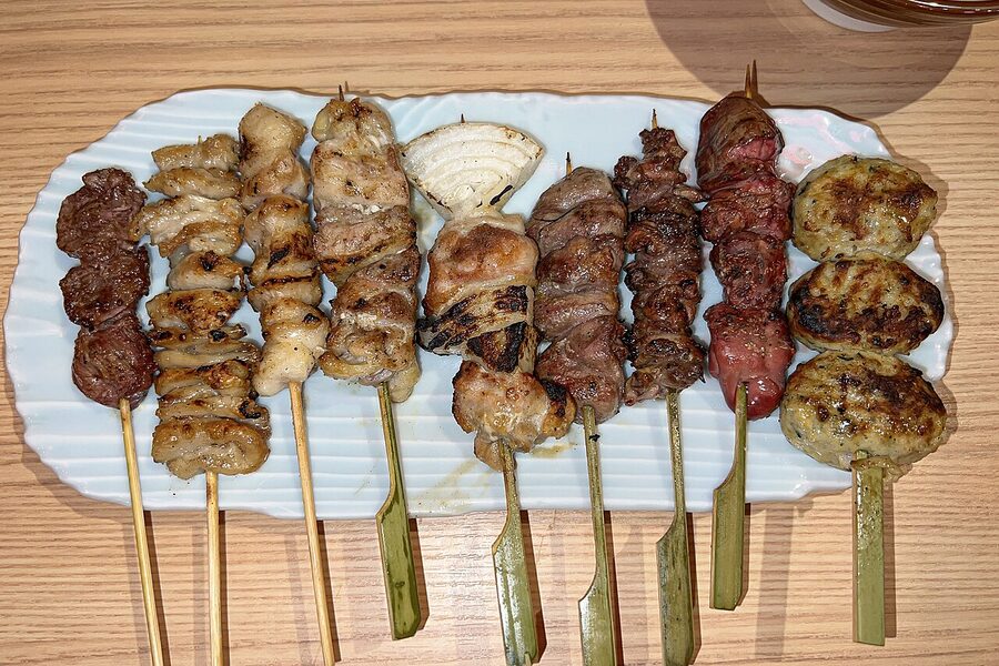 Assorted yakitori skewers with beer and small side dishes on a counter at a Tokyo izakaya
