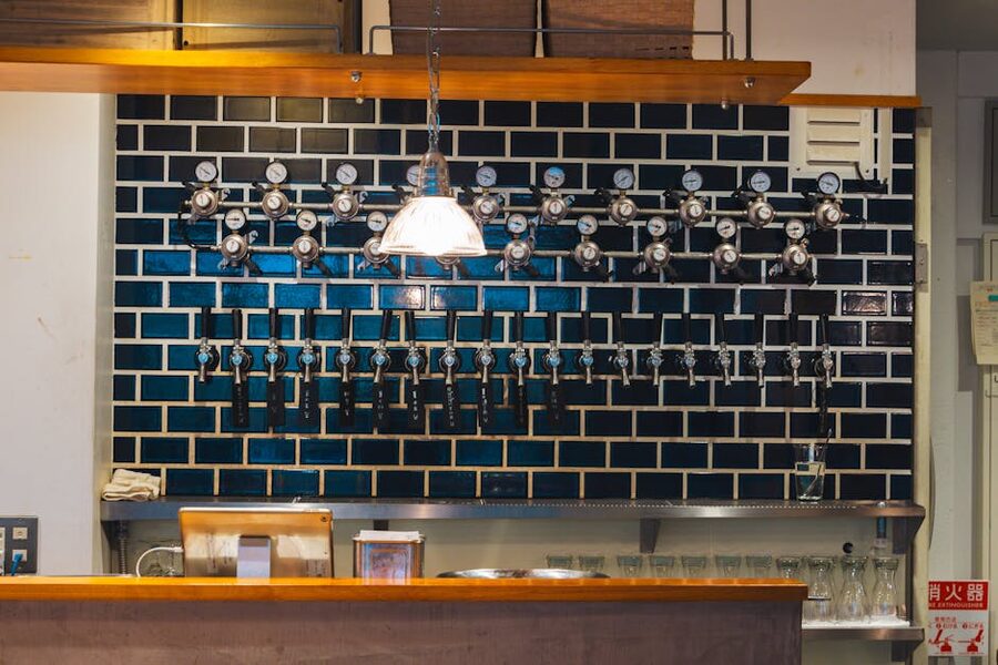 Craft beer taps and bottles lined up along a wooden bar in a modern Tokyo taproom