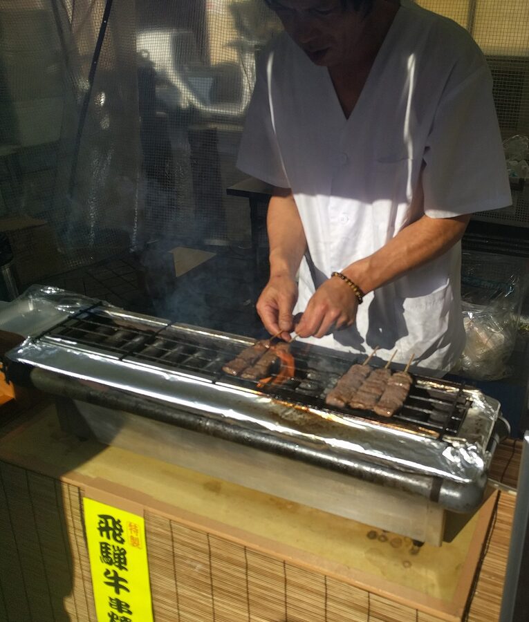 Hida beef skewers grilling at a Takayama street food stall