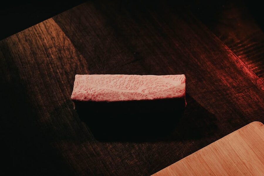 Marbled wagyu beef sliced on a rustic dark wooden surface