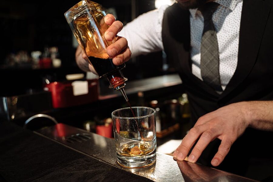 Bartender pouring whisky into a glass at a bar counter