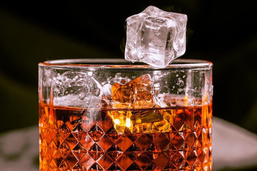 Whisky in a cut-glass tumbler with a single ice cube