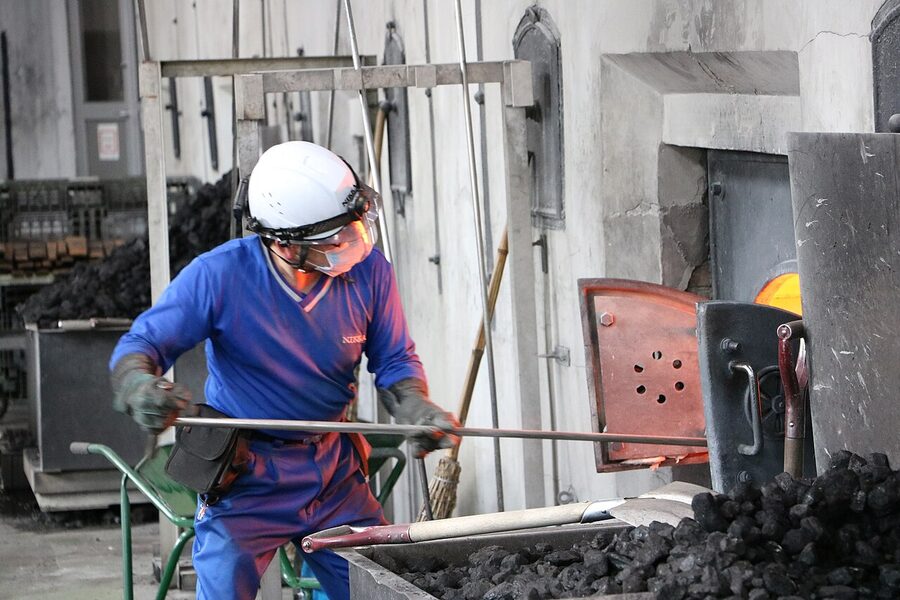 Worker shovelling coal into a pot still at Nikka Yoichi distillery in Hokkaido