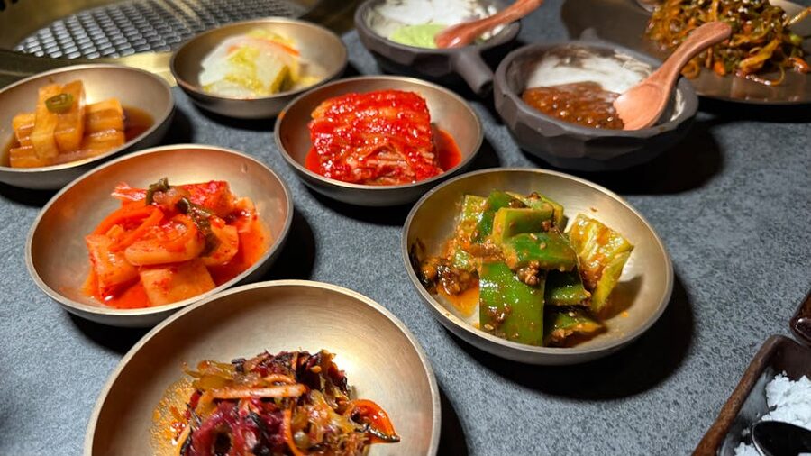 A variety of Korean banchan side dishes served in metallic bowls