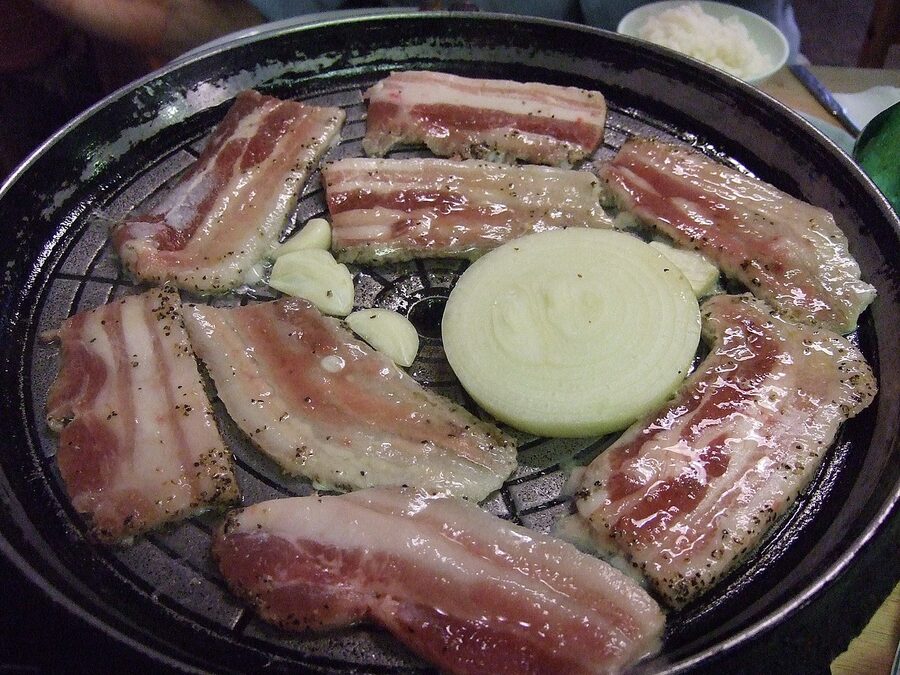 Samgyeopsal Korean pork belly grilling on a table top grill