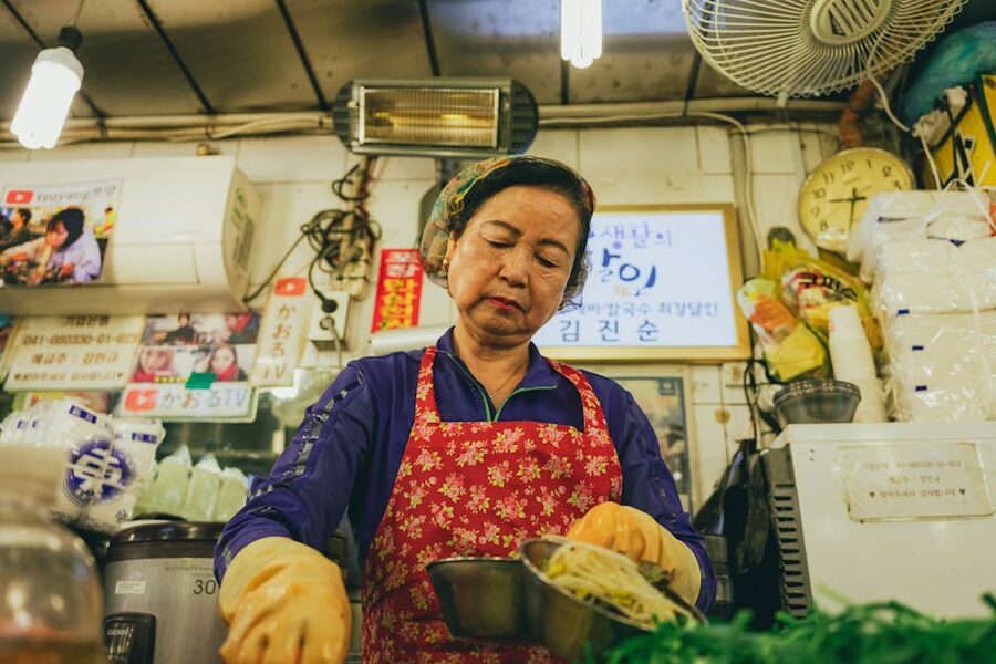 A Korean vendor preparing traditional food at a Seoul market stall
