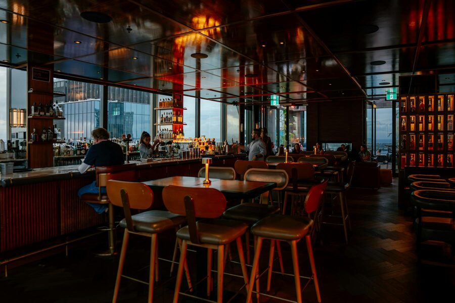 Warm dimly lit rooftop bar interior with city skyline view