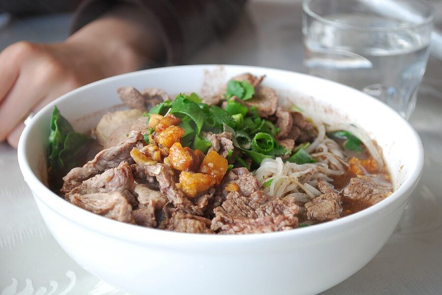 Bowl of Thai boat noodles with dark broth and beef