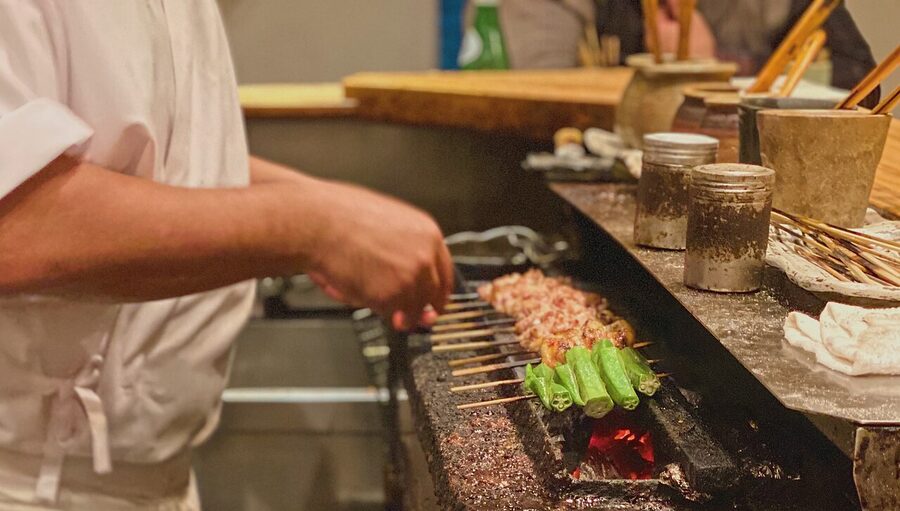 Yakitori chef grilling chicken skewers