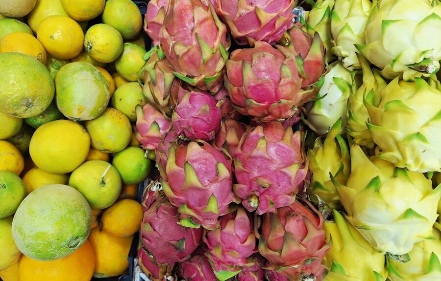 Dragon fruit displayed alongside citrus at a Southeast Asian market