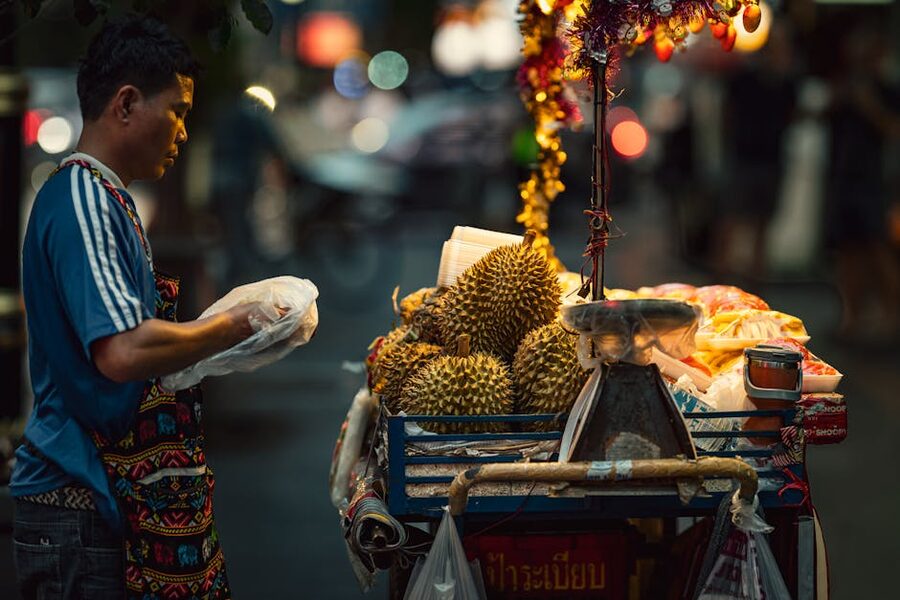 Durian vendor cracking open the fruit at a Bangkok night market