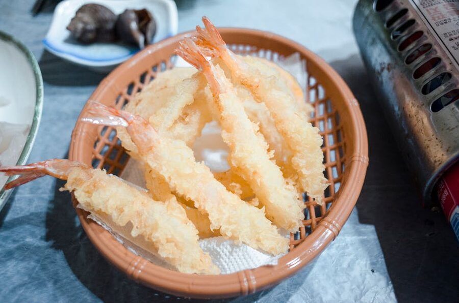 Crispy shrimp tempura served in a woven basket, typical at Kyoto tempura counters